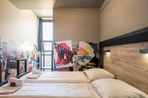 2 camas en una habitación con carteles en la pared en a&o Antwerpen Centraal, en Amberes