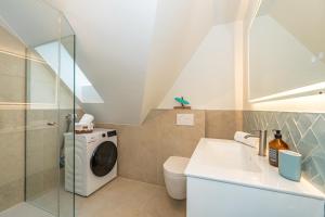 ein Badezimmer mit Waschmaschine und Waschbecken in der Unterkunft Syltweh in Munkmarsch