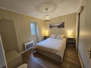 een slaapkamer met een bed en twee nachtkastjes en twee lampen bij Maison perouge in Soustons