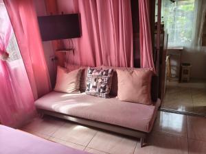 a couch in a room with pink curtains at Creole Cottage Homestay in Mahe