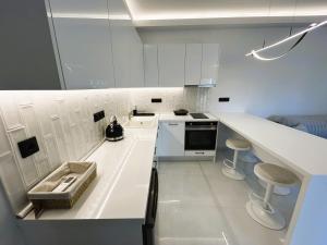 a white kitchen with a counter and stools in it at Ghini Venes 3 in Tríkala