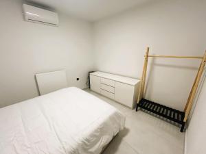 a white bedroom with a bed and a radiator at Ghini Venes 3 in Tríkala +1 photo