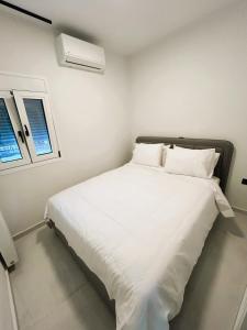a bedroom with a large white bed with two windows at Ghini Venes 3 in Tríkala