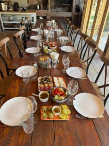 a long wooden table with plates and bowls of food at Nikalas Marani in Gurjaani