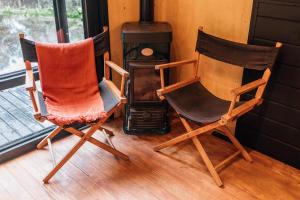 Zwei Stühle stehen vor einem Holzofen. in der Unterkunft Cabana Fora in São Francisco de Paula + 7 Fotos