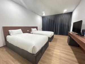 una camera d'albergo con due letti e una TV a schermo piatto di J&P Hotel Sriracha a Ban Hua Na