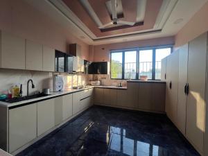 een keuken met witte kasten en een groot raam bij Riyaanz aesthetic in Hyderabad