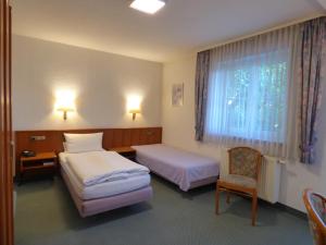 a bedroom with two beds and a chair and a window at Pension Meyer in Rimpar