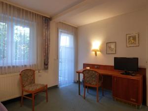 una camera d'albergo con scrivania, TV e sedie di Pension Meyer a Rimpar