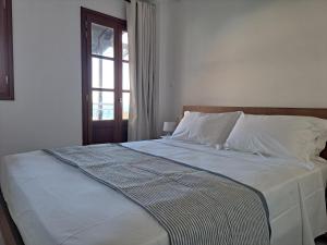 un letto con lenzuola bianche e una finestra in una stanza di Downtown Apartment Platanos a Panteli