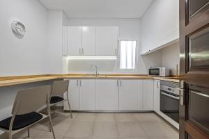 een keuken met witte kasten en een tafel en stoelen bij Reis by KAAMAH in Ribeira Brava