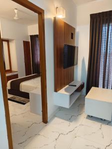 グルヴァイアールにあるSree Nandhanam Nivasのベッドと壁掛けテレビのある寝室 +2枚の写真