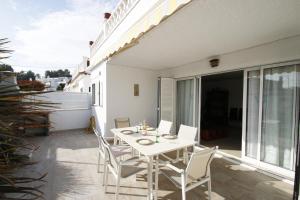 Un patio con una mesa blanca y sillas en un balcón. en Casa Lara, en Miami Platja