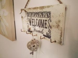 a sign that reads welcome friends hanging on a wall at B&B Le Rose in Santa Maria di Castellabate