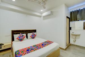 ein weißes Schlafzimmer mit einem Bett mit bunten Kissen in der Unterkunft FabHotel Wild Wings Gachibowli in Hyderabad