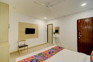 ein Schlafzimmer mit einem Bett und einem Stuhl und einem Fernseher in der Unterkunft FabHotel Wild Wings Gachibowli in Hyderabad