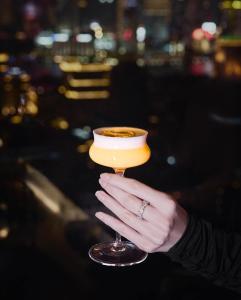 een vrouw die een glas met een drankje vasthoudt bij Hotel Vip70 Jaen Perú in Jaén