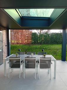 un tavolo bianco e sedie in un patio con una finestra di LE CLOS DU MONTYS a Louveigné