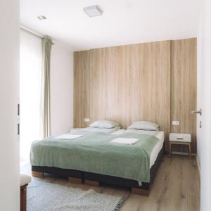 Un dormitorio con una cama grande con una manta verde. en Katáng Vendégház, en Tardosbánya