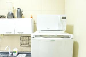 a microwave on top of a refrigerator in a kitchen at Ap7 - Studio Completo a Minutos das Compras no Paraguai in Guaíra +8 photos