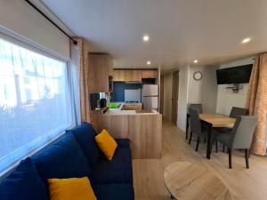 Bungalow Cinéric Nouveau 2026 في كانيه ان روسيلون: غرفة معيشة مع أريكة زرقاء ومطبخ