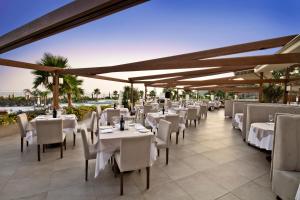 um restaurante com mesas brancas e cadeiras num pátio em Sianji Well-Being Resort em Turgutreis