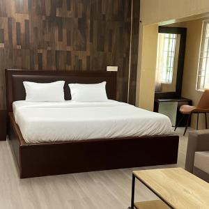 a bedroom with a large bed with a wooden wall at Coromandel Suites in Chennai