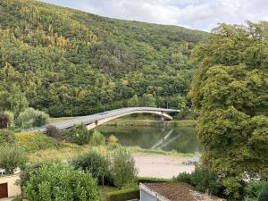 un pont sur une rivière avec une montagne dans l'établissement Gîte des Prés, à Revin