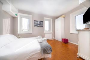 1 Schlafzimmer mit einem weißen Bett und 2 Fenstern in der Unterkunft Appartamento alle Mura in Cividale del Friuli