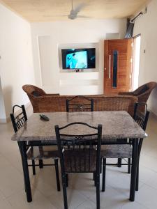 a dining room table with chairs and a tv on the wall at majaoni villa in Mombasa