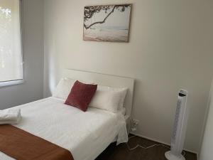 een slaapkamer met een bed met witte lakens en rode kussens bij Frankston Vacation Home in Frankston East