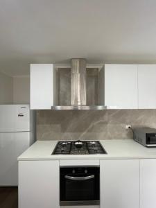 een keuken met witte kasten en een kookplaat oven bij Frankston Vacation Home in Frankston East