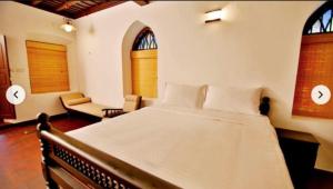 a bedroom with a large white bed and two windows at The Heritage By Boho Travelista in Cochin +25 photos