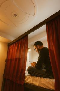ニューデリーにあるCozy Inn Hostelの携帯電話を見ながら座っている男