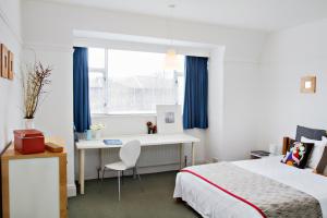 a bedroom with a bed and a desk and a window at SPACIOUS Apartment in London