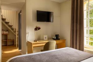 Un dormitorio con un escritorio y un televisor en la pared. en Hôtel Le Pré Galoffre, en Nimes