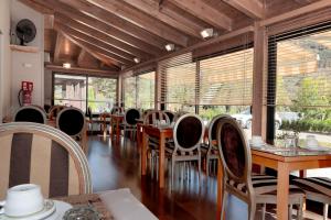 Un comedor con mesas y sillas y ventanas. en Hotel Blu Aran, en Vielha