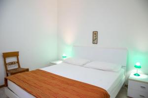 una camera da letto con un grande letto bianco e una sedia di Pine-front bungalow steps from the beach a Marina di Santa Croce