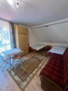 a room with two beds and a table and a rug at Pokoje gościnne u Faronow in Muszyna