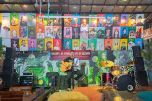 a man sitting on a stage playing a guitar at SECRET GARDEN Hostel - WANDERNEST Cat Ba in Cat Ba