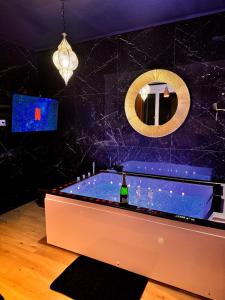 La salle de bains est pourvue d'une baignoire et d'une bouteille de vin. dans l'établissement Jacuzzi privé, Sauna & Design Chic, à Reims