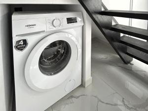 a white washing machine sitting under a staircase at NEKTAR home in Latsídha