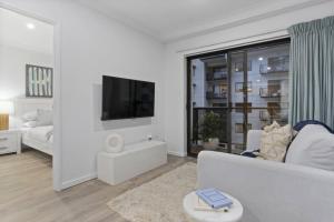 een witte woonkamer met een bank en een tv bij Cityscape on Mounts Bay in Perth