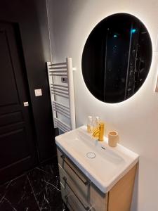 une salle de bains avec un lavabo et un miroir dans l'établissement Jacuzzi privé, Sauna & Design Chic, à Reims
