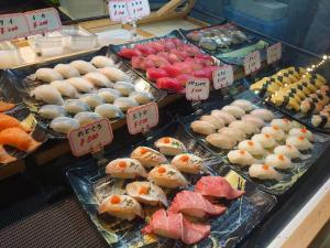 Una exhibición de sushi y otros alimentos en una tienda. en インジホテル下関, en Shimonoseki
