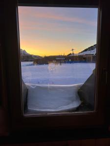 a window with a view of a snow covered field at Dinastia Case Snow Apartment in Passo del Tonale