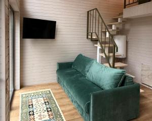 ein Wohnzimmer mit einer grünen Couch und einer Treppe in der Unterkunft Зелено Східниця in Schidnyzja