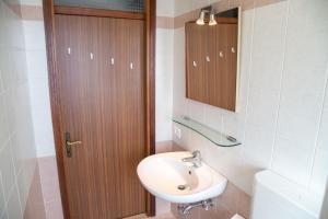 um banheiro com uma pia e uma porta de madeira em Centric apartment by the beach em Eraclea Mare mais 17 fotografias