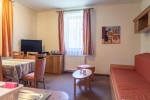a room with a bed and a couch and a table at Lomnica Orange Apart in Tatranská Lomnica