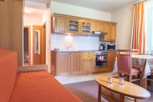 a kitchen with wooden cabinets and a table in a room at Lomnica Orange Apart in Tatranská Lomnica